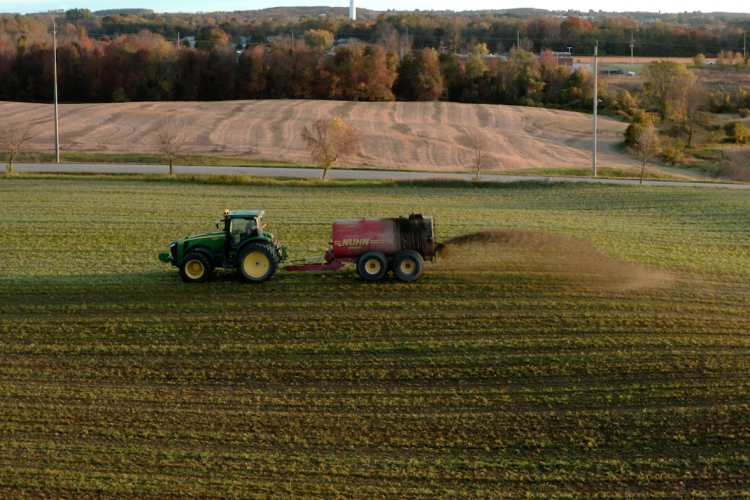 tractor spreading liquid manure on a green field